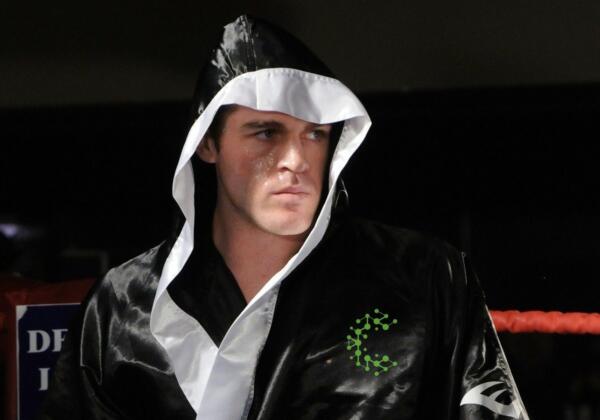 Johnny Bourke in a Carbon Gym robe standing in the ring, Muay Thai weight loss transformation story