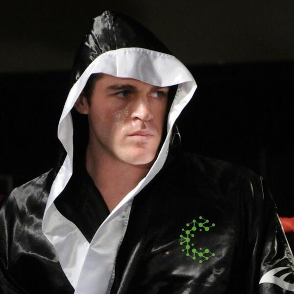 Johnny Bourke in a Carbon Gym robe standing in the ring, Muay Thai weight loss transformation story