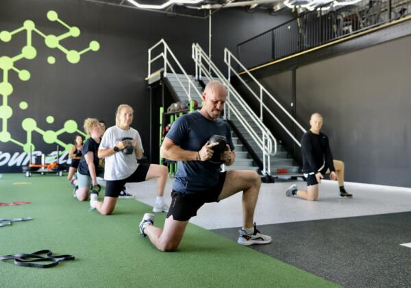 Group fitness class doing kettlebell lunges on the turf track at Carbon Gym Geelong