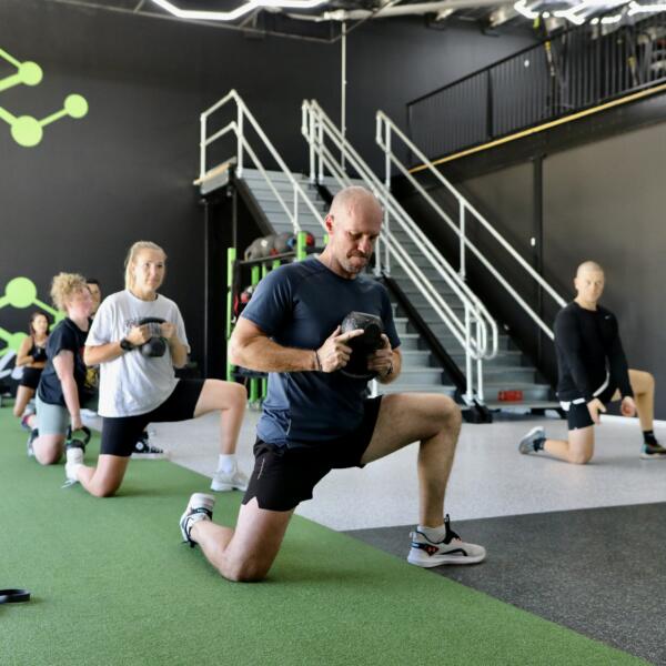 Group fitness class doing kettlebell lunges on the turf track at Carbon Gym Geelong