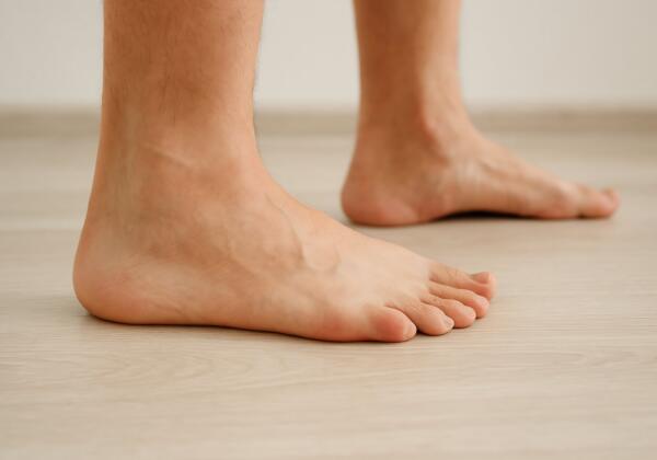 Close-up of bare feet standing on a wooden floor, illustrating foot health and mobility