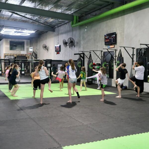 Group of kids doing warm-up drills during a martial arts class on the mats at Carbon Gym Geelong