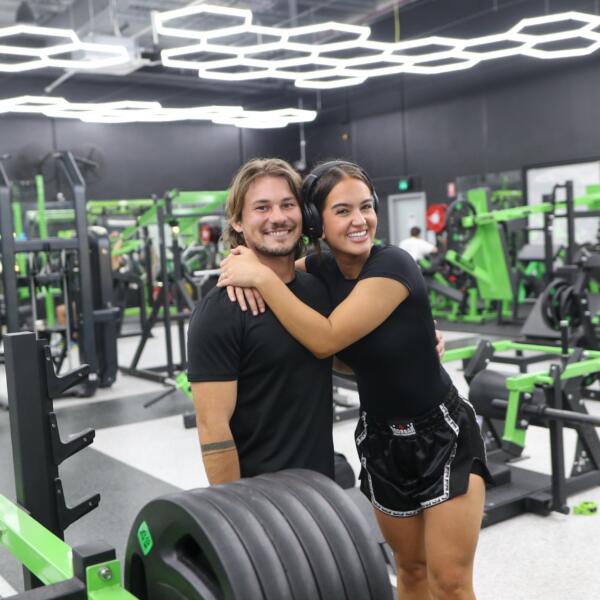 Two smiling members on the strength floor surrounded by weights equipment at Carbon Gym Geelong