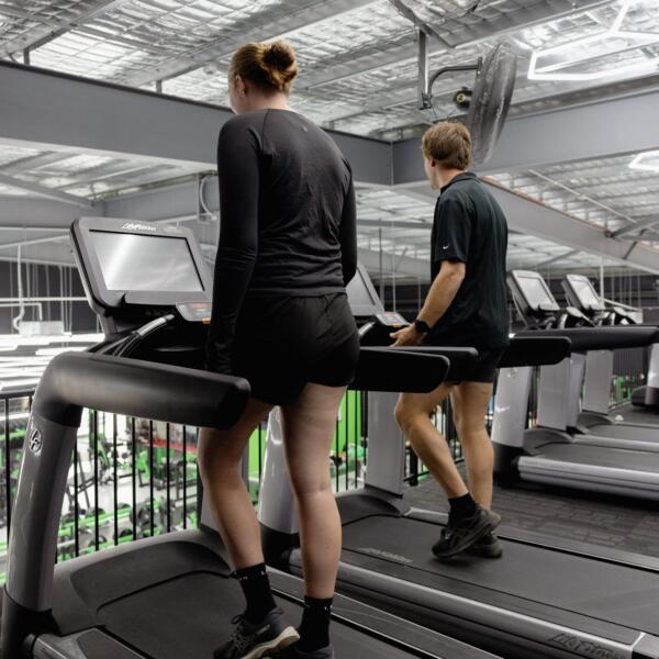 Two members walking on treadmills on the cardio deck overlooking the weights floor at Carbon Gym Geelong