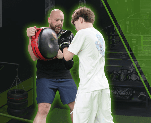 A coach holding pads for a young student during a kids martial arts class at Carbon Gym in North Geelong