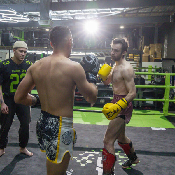 Two fighters sparring in the boxing ring at Carbon Gym Geelong's Studio 5, with a coach in a Carbon Gym shirt supervising