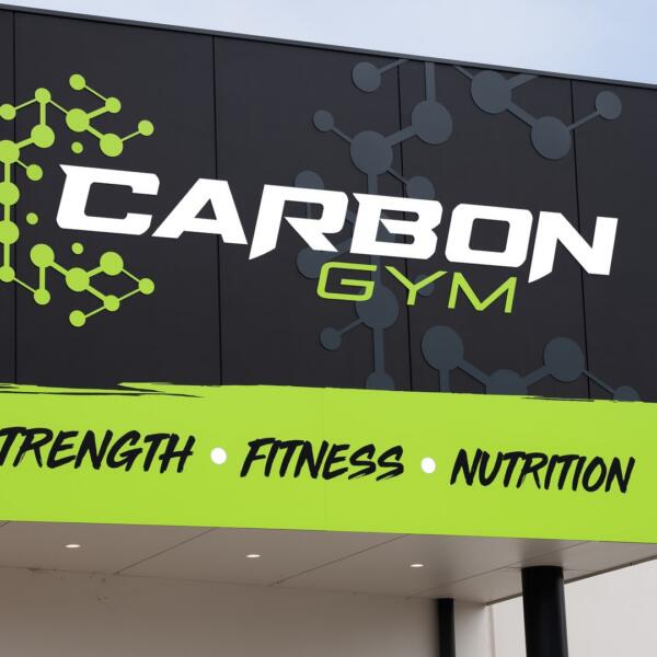Exterior building signage reading CARBON GYM in white and green with the words Strength, Fitness, Nutrition below.