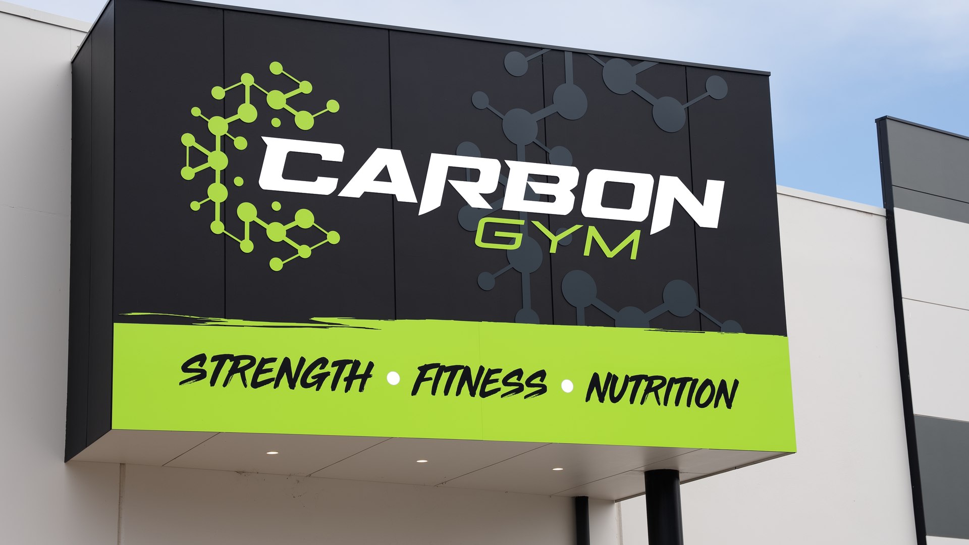 Exterior building signage reading CARBON GYM in white and green with the words Strength, Fitness, Nutrition below.