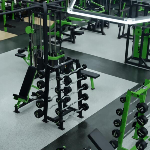 High-angle shot of a gym floor showing dumbbell racks, a cable machine, and kettlebells under hexagon ceiling lights.