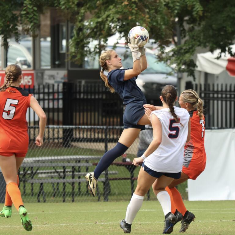 Heidi Harris catching a high ball above a crowd of players