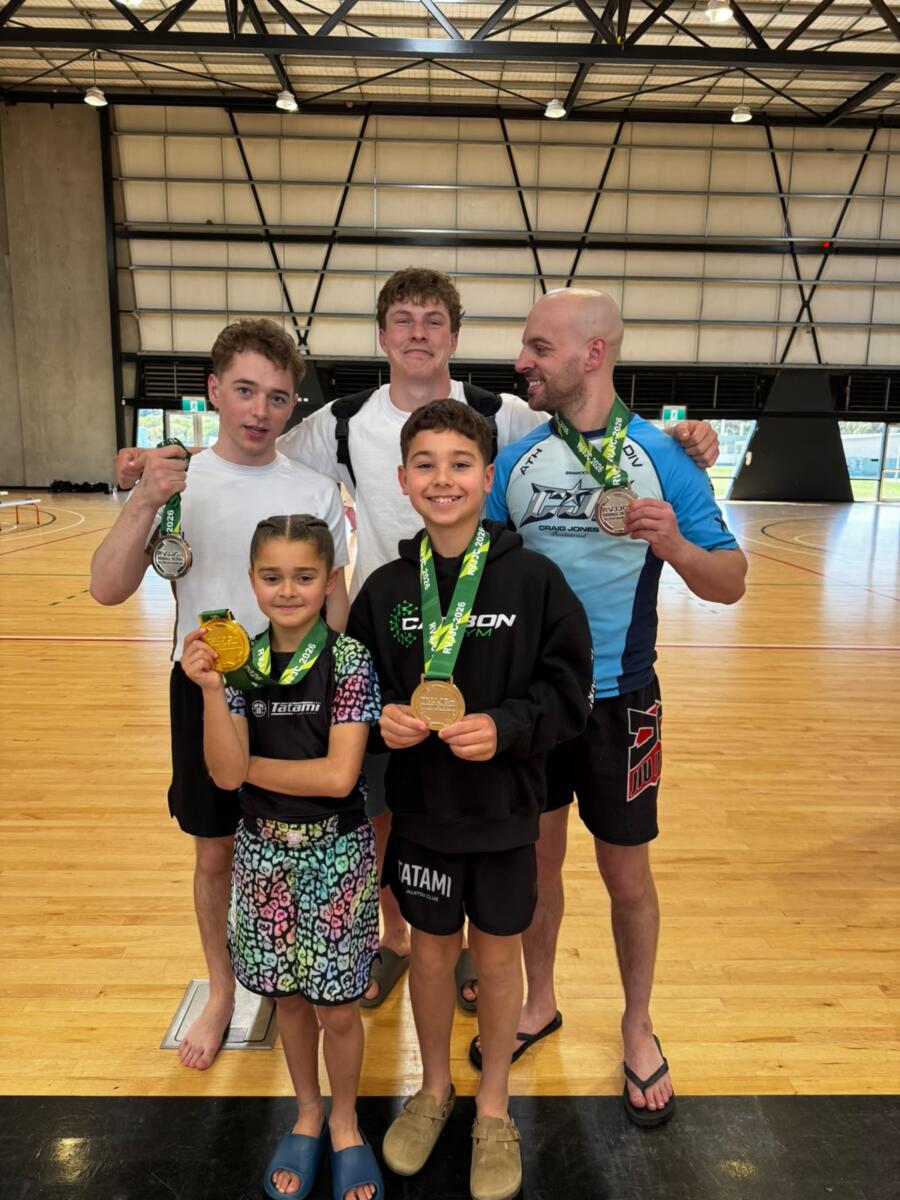 Five Carbon Gym BJJ athletes, two kids in front and three adults behind, holding medals at the Regional Victoria Jiu Jitsu Championships in Torquay
